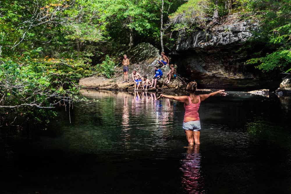 A customer in the ROcky river looking at her College group swimming in the river.